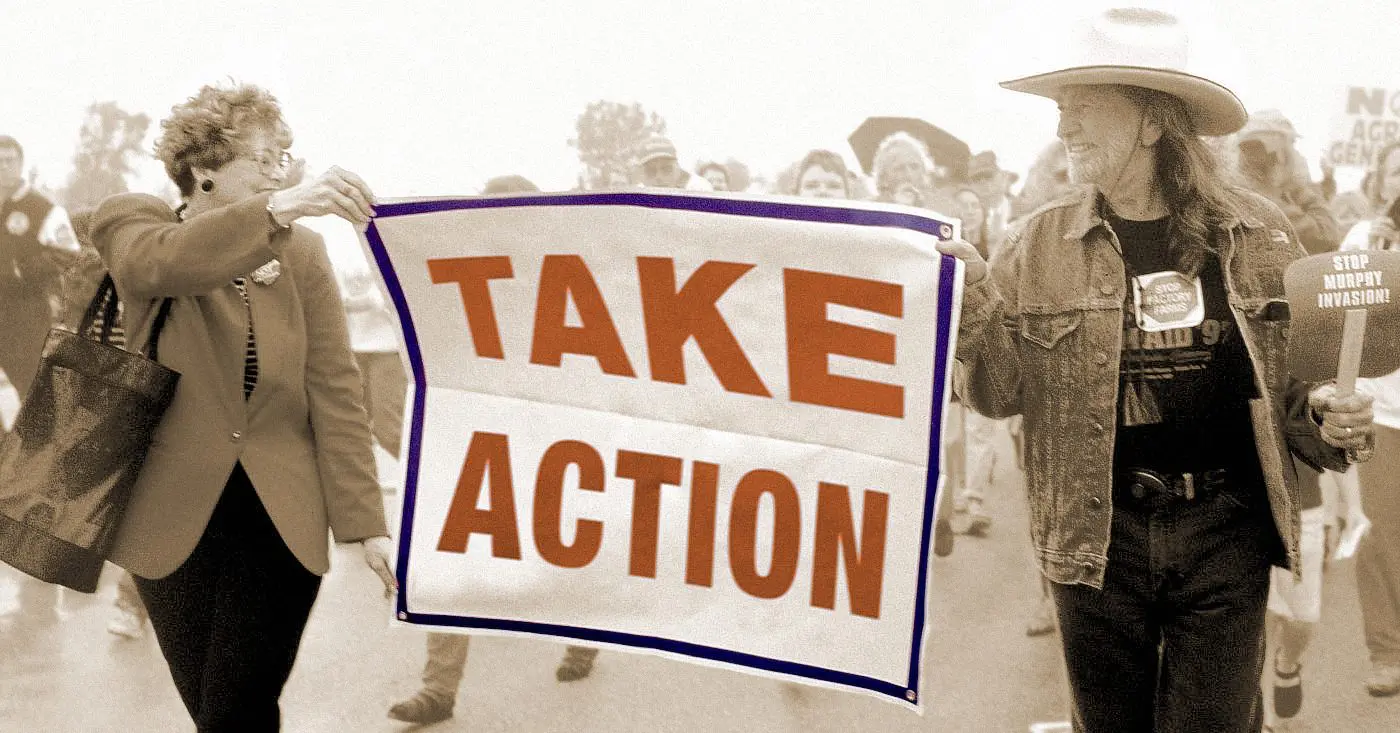 TAKE ACTION sign being held by Willie Nelson at a rally