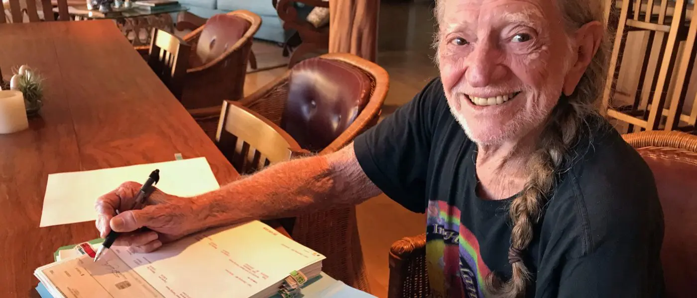 Willie Nelson signing Farm Aid grant checks