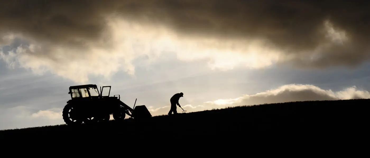 farmer in field with tractor in shadow