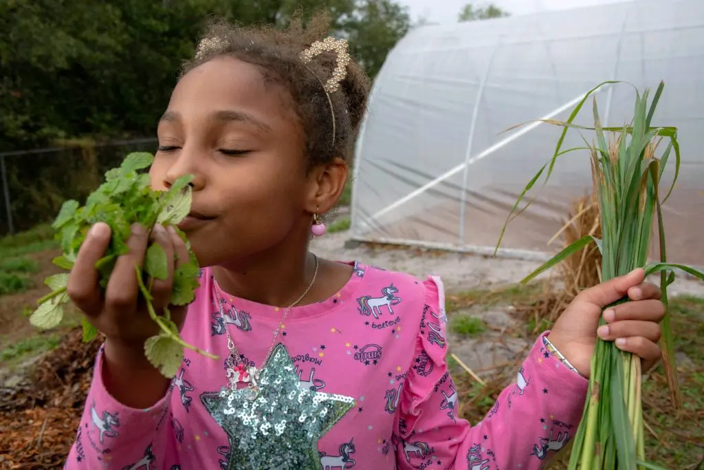 A Campesinos' Garden member smells her harvest.