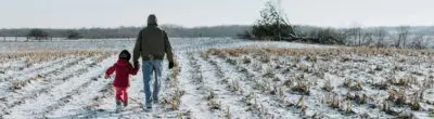 parent and child walking in a snowy field