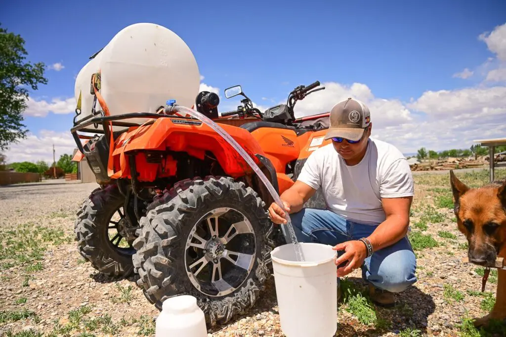 man filling a bucket in front of a tractor