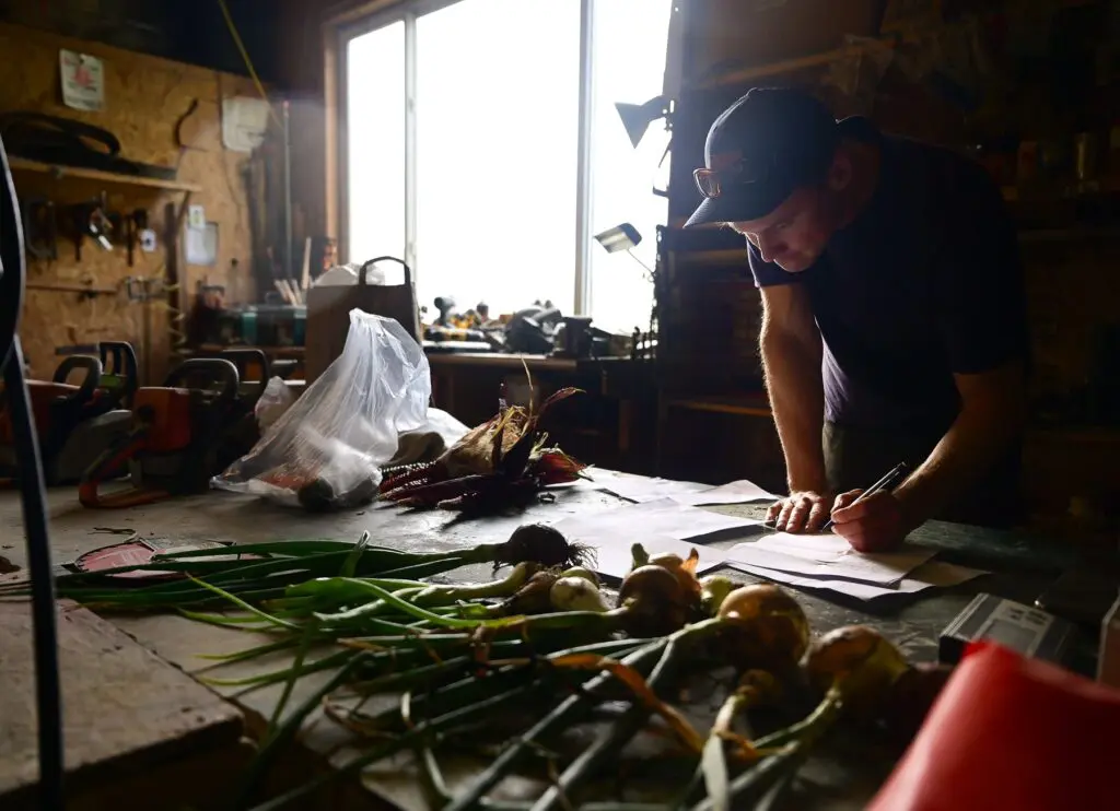 man with a pen looking at papers on a barn table