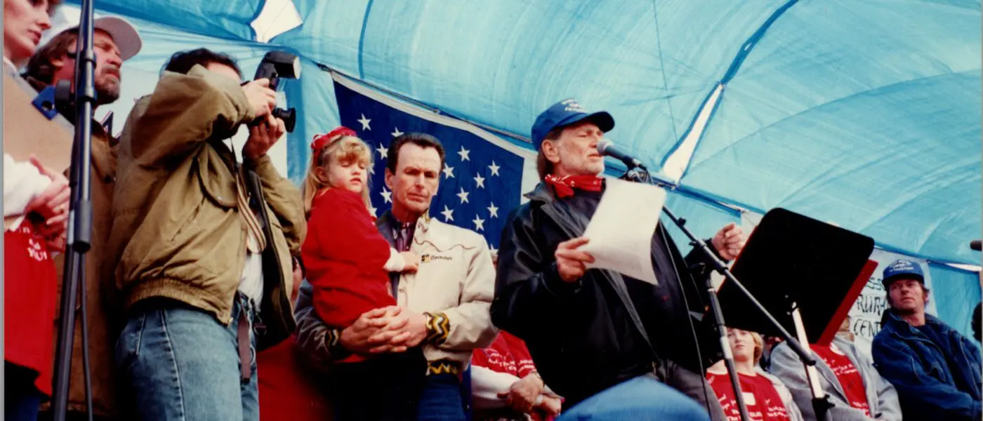 willie nelson and others stand on stage