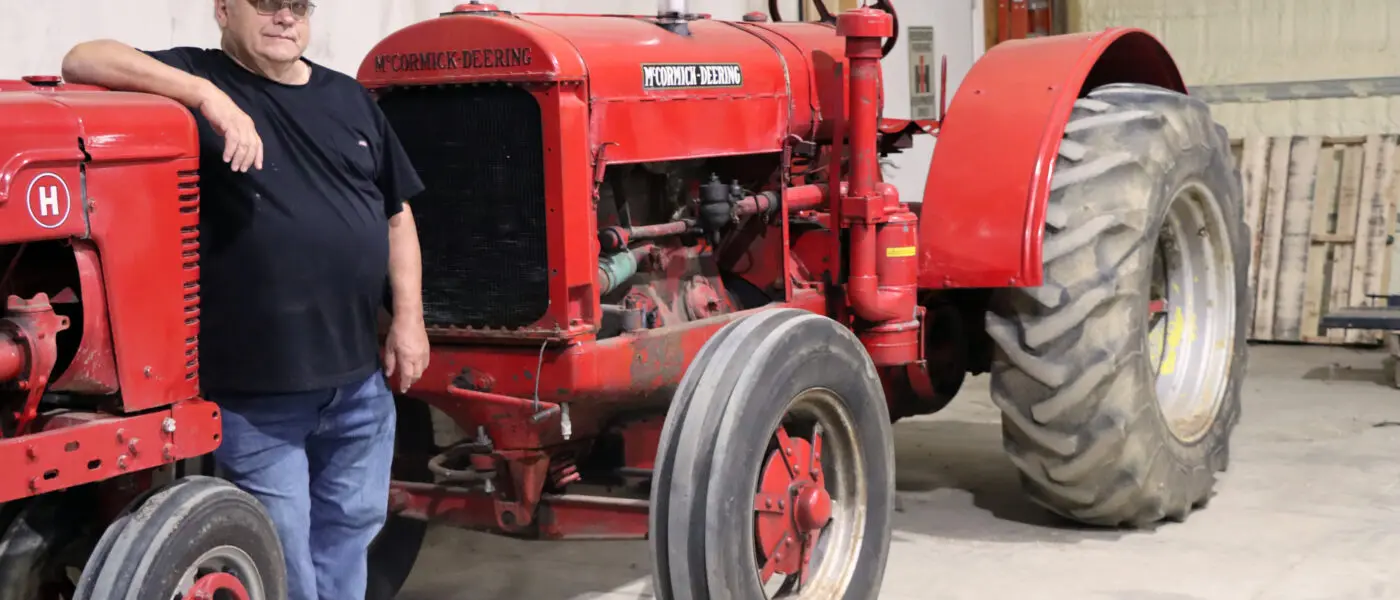farmer standing next to antique tractors