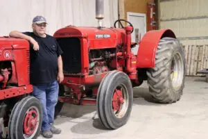 farmer standing next to antique tractors
