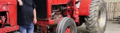 farmer standing next to antique tractors