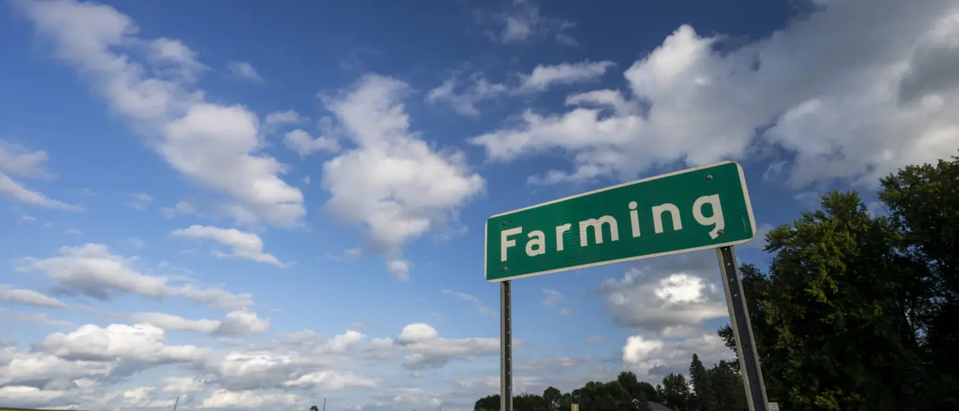 field with a road in front of it with a sign that says FARMING