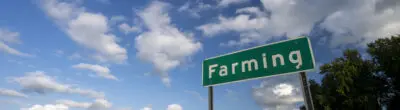 field with a road in front of it with a sign that says FARMING