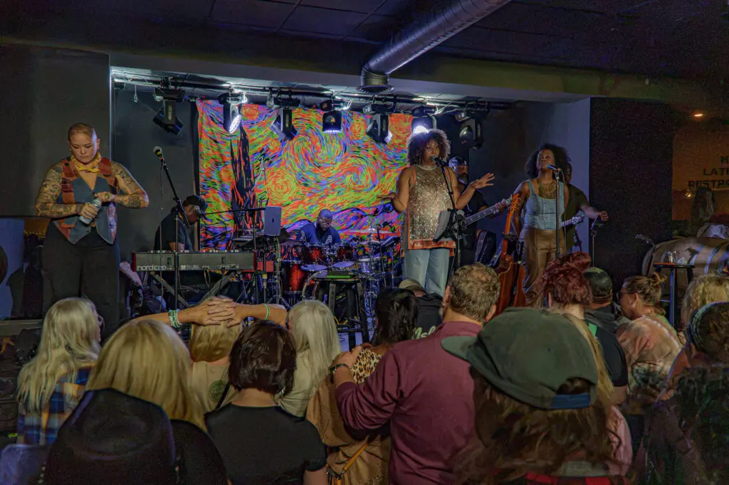 Rebecca Porter, Rissi Palmer and Roberta Lea performing on stage with a crowd watching