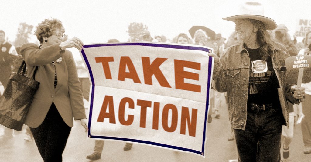 Willie Nelson marching with sign that says TAKE ACTION