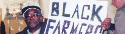Black farmer holds signs that reads Black farmers demand fair prices