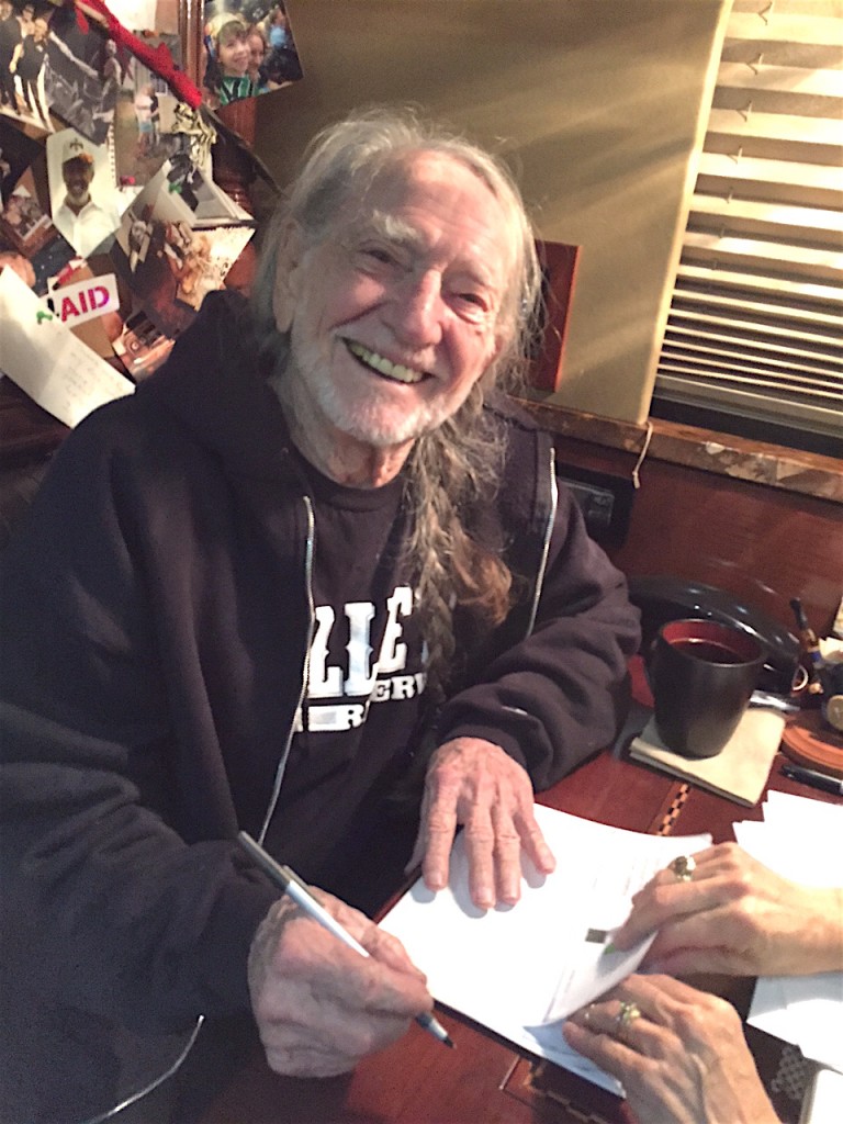 Willie Nelson, Farm Aid’s Founder and President, signing the congratulatory letters and checks for our 2015 grant recipients.