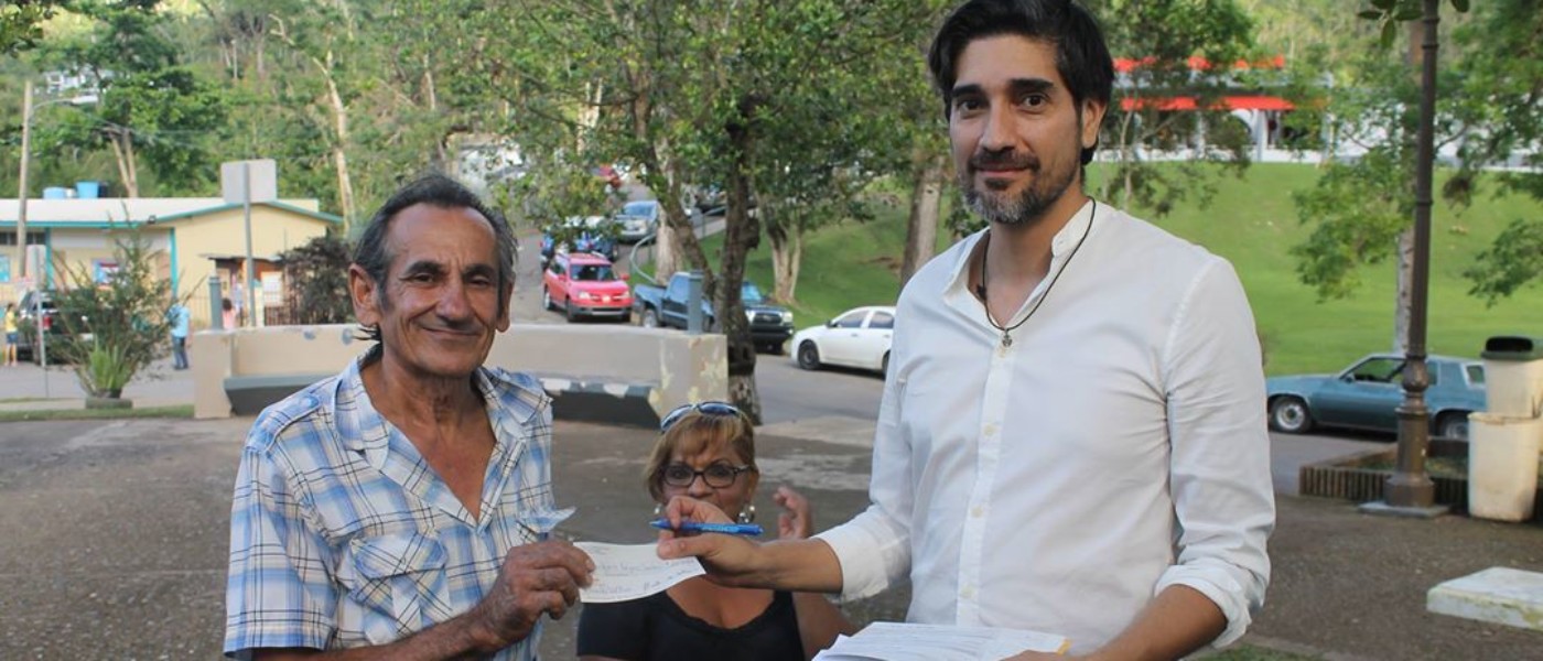 Arturo Roldán of Visit Rico presents a check to farmer Norberto Rodríguez Sánchez.