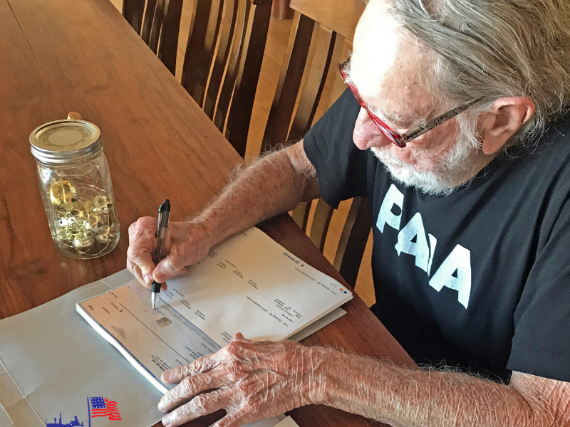 Willie Nelson signing Farm Aid 2019 grant checks