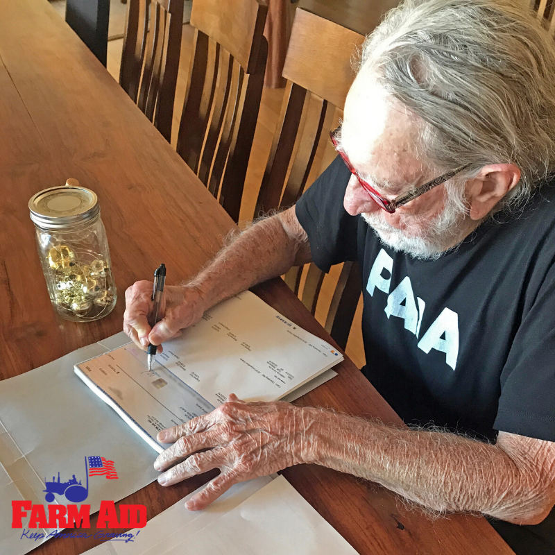 Willie Nelson signing Farm Aid 2019 grant checks