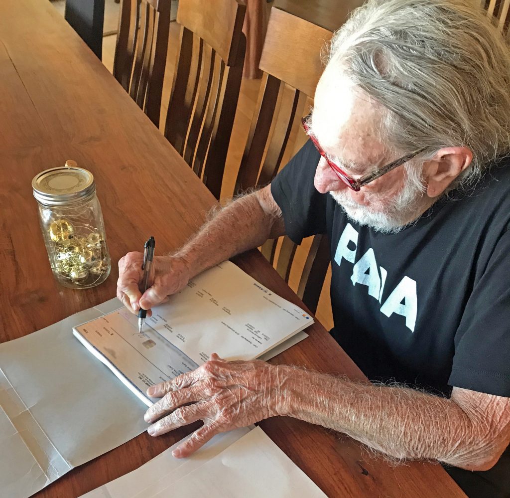 Willie Nelson signing Farm Aid 2019 grant checks