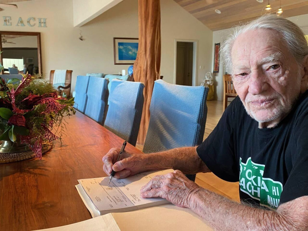 Willie Nelson signing Farm Aid grant checks in 2022