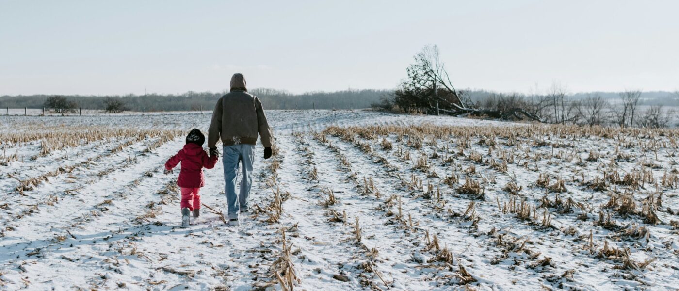 parent and child walking in a snowy field