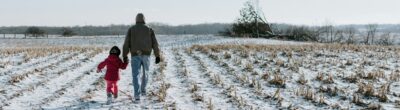 parent and child walking in a snowy field
