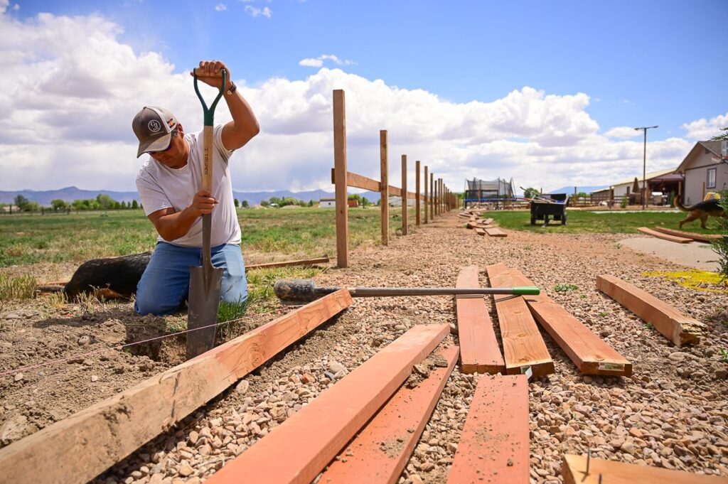 A man is working on building a fence