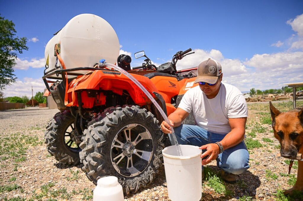 man filling a bucket in front of a tractor