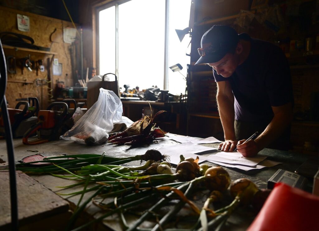 man with a pen looking at papers on a barn table