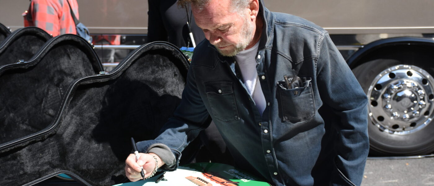 John Mellencamp signing a guitar