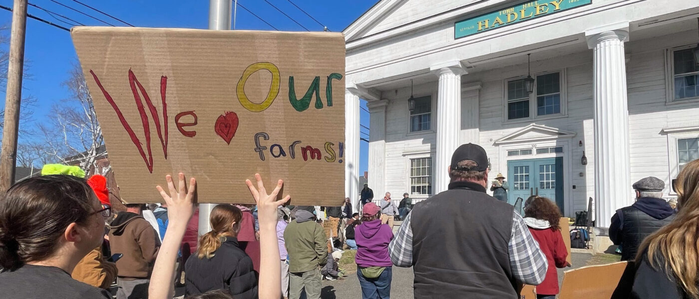 child holding a sign at a rally that says "We [heart symbol] our farmers"