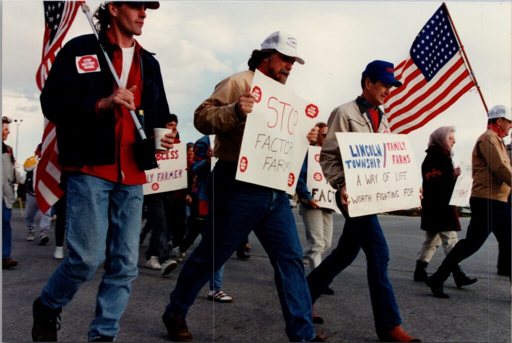 people holding signs marching against factory farms