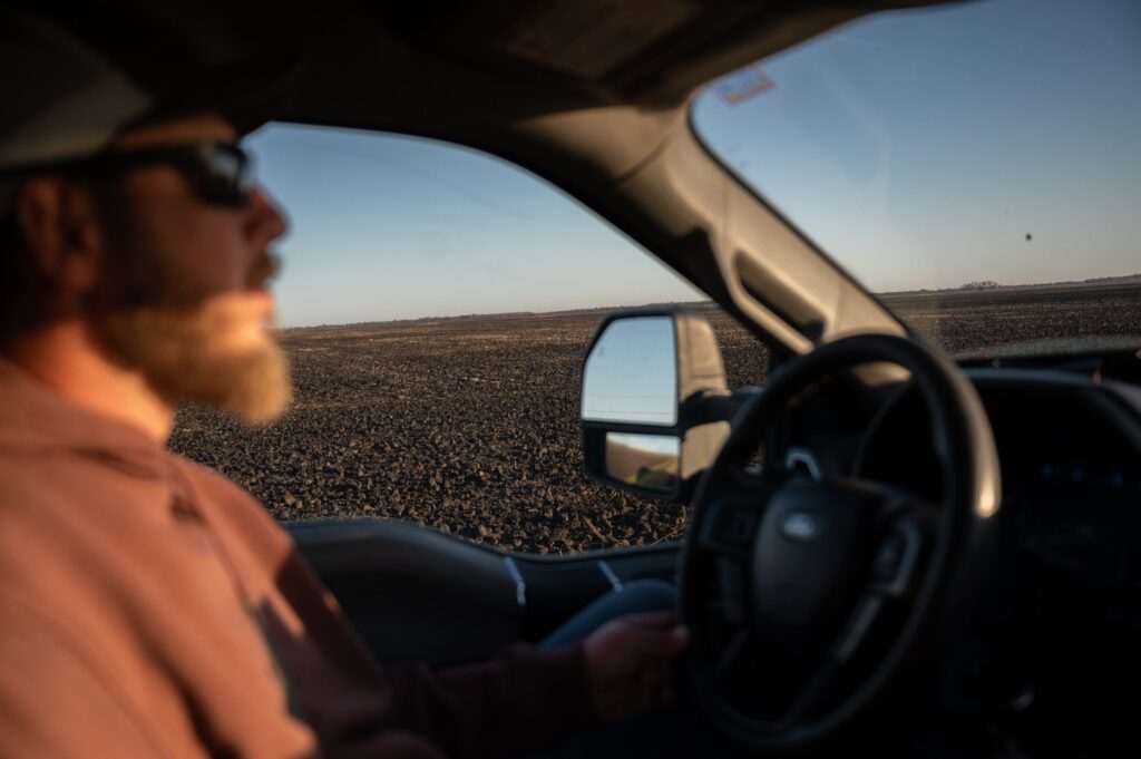 man driving past a field