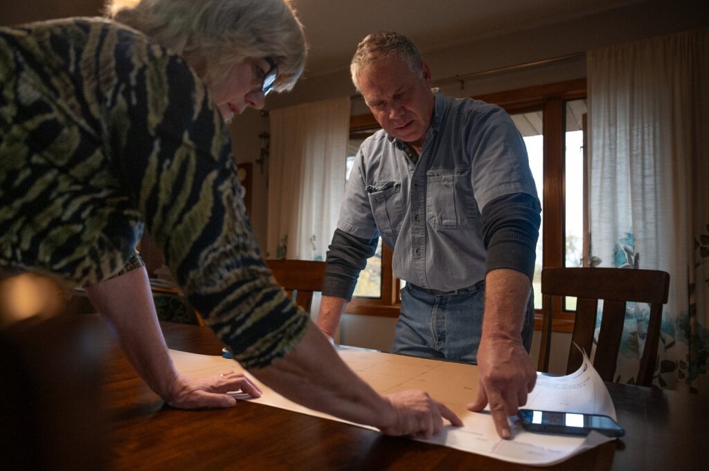 a couple stand over a paper at a table