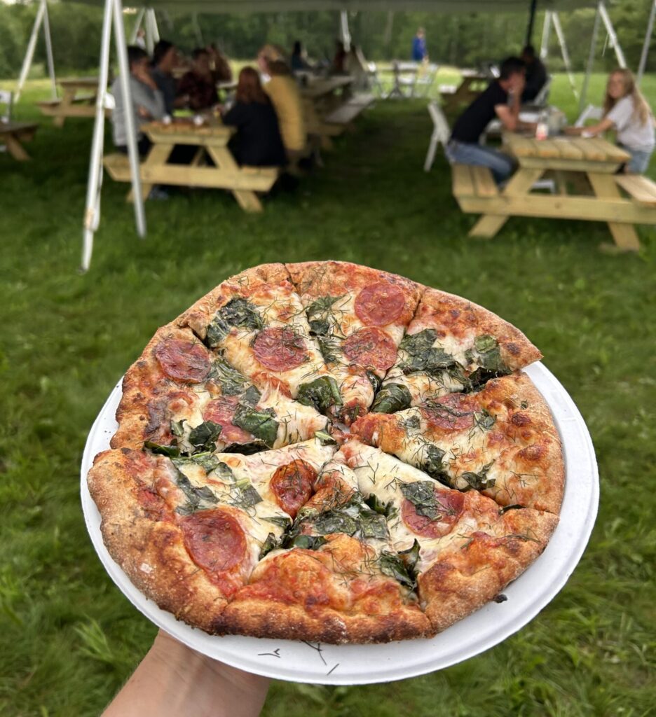 pizza on a plate outside a tent on a farm